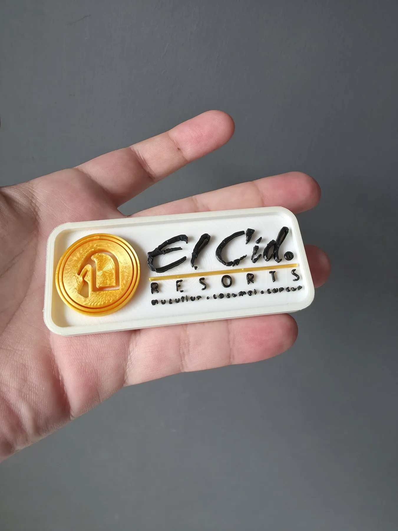 Bag tag de El Cid Resorts sostenido en la palma de una mano, que muestra su tamaño real