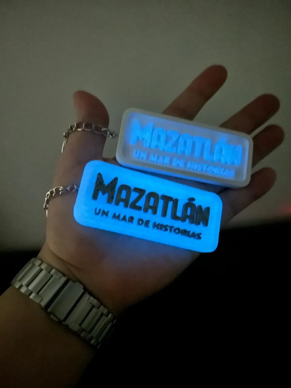 Llaveros fosforescentes de Mazatlán sostenidos en una mano, brillando en la oscuridad
