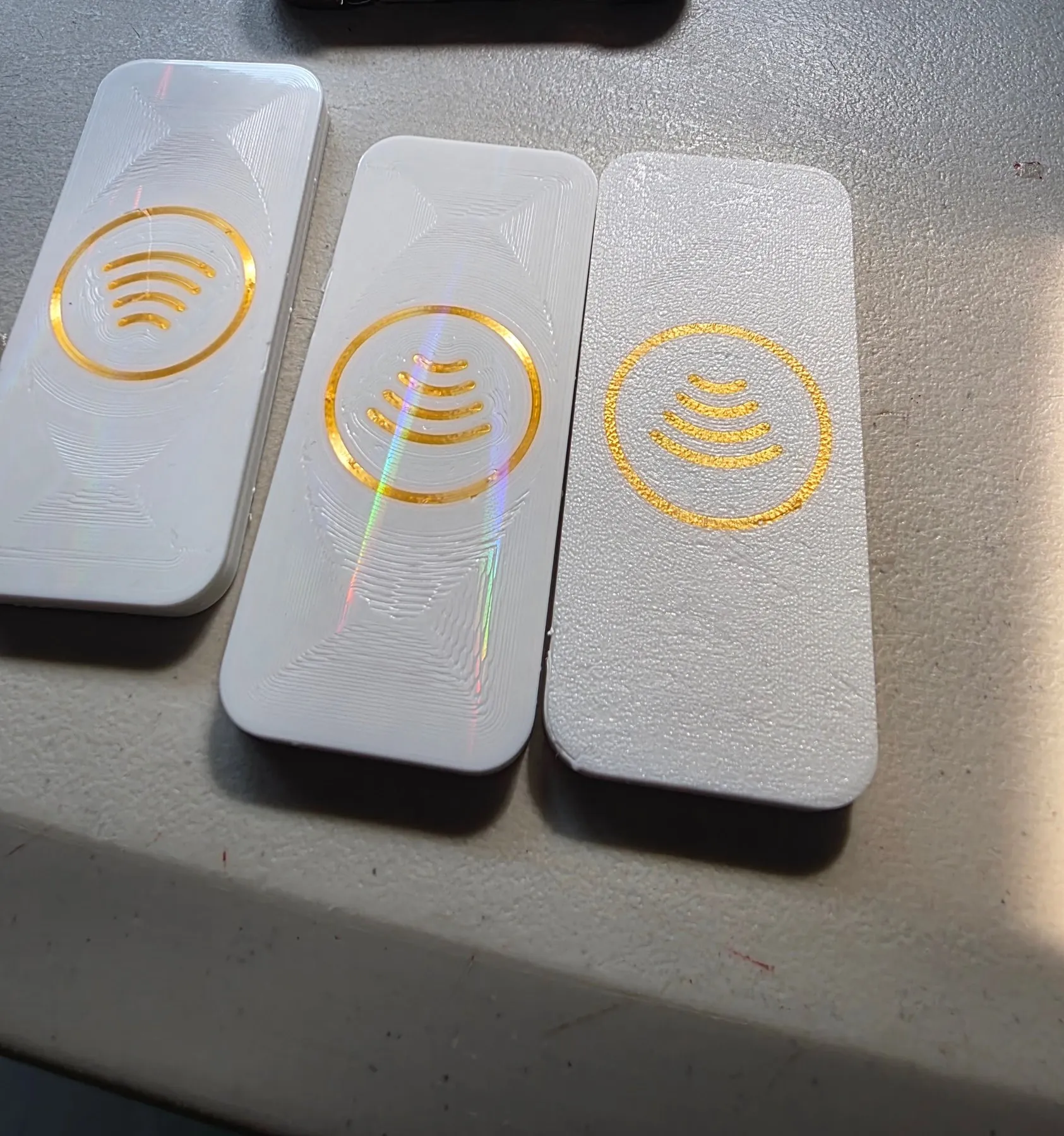 Tres etiquetas NFC blancas alineadas, cada una con un acabado de superficie distinto